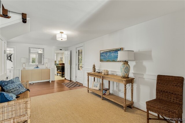 living area with light wood finished floors, wainscoting, and a decorative wall