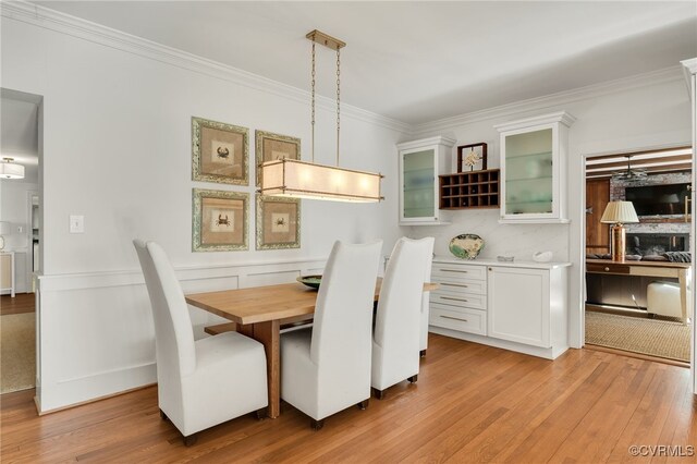 dining space featuring light wood-style floors and crown molding