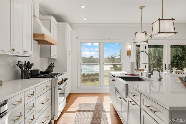 kitchen with custom exhaust hood, ornamental molding, white cabinetry, light wood-type flooring, and high end white range