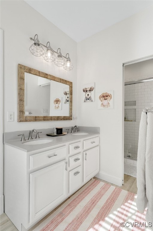 full bath with a stall shower, a sink, baseboards, and double vanity