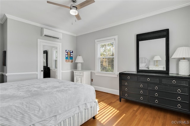 bedroom with ceiling fan, wood finished floors, baseboards, a wall mounted AC, and crown molding