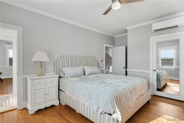 bedroom featuring ornamental molding, an AC wall unit, multiple windows, and light wood-style flooring