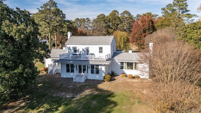 back of house featuring entry steps, a yard, a chimney, and a balcony