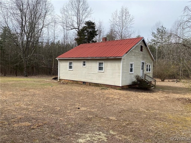 view of property exterior featuring entry steps, metal roof, and a chimney