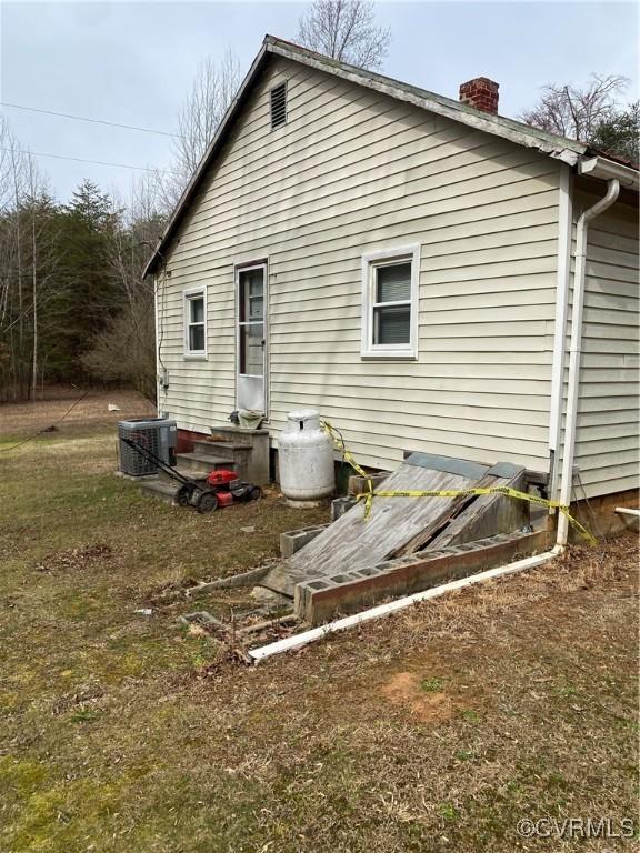 back of property featuring a chimney and cooling unit