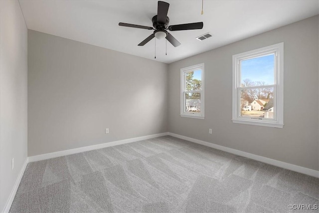 carpeted empty room featuring baseboards, visible vents, and a ceiling fan