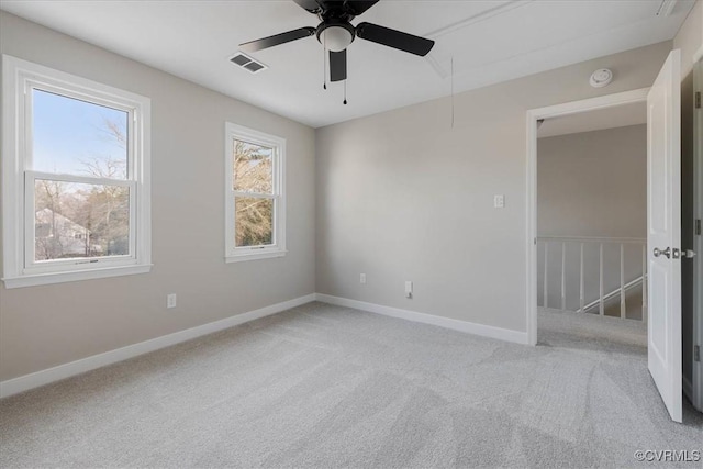 unfurnished room featuring light carpet, attic access, visible vents, baseboards, and ceiling fan