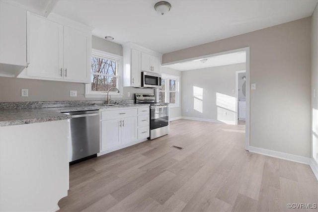 kitchen with visible vents, light wood-style flooring, appliances with stainless steel finishes, white cabinetry, and a sink