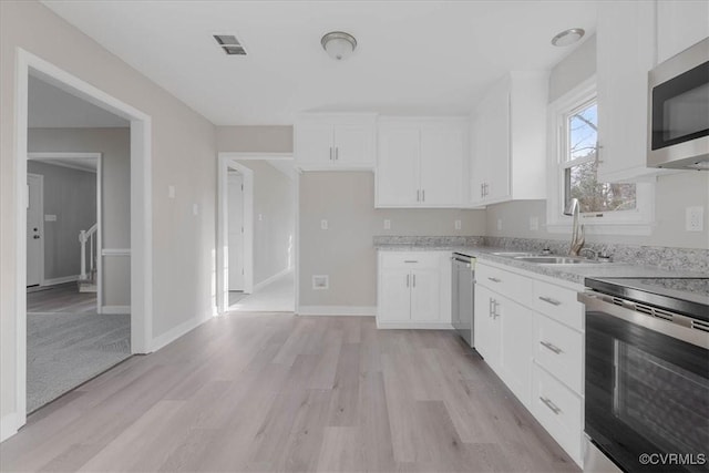 kitchen with a sink, visible vents, light wood-style floors, white cabinets, and appliances with stainless steel finishes