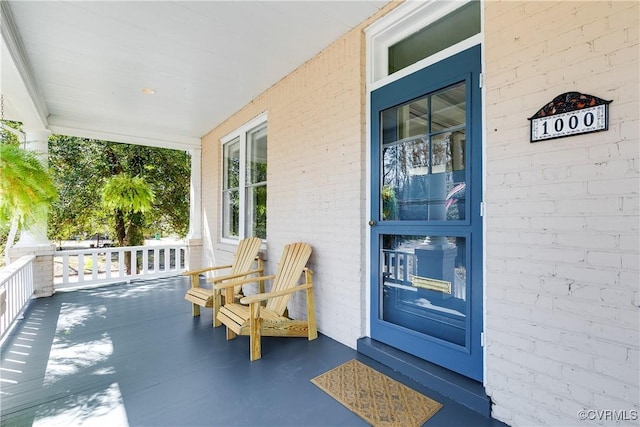 view of exterior entry with brick siding and covered porch