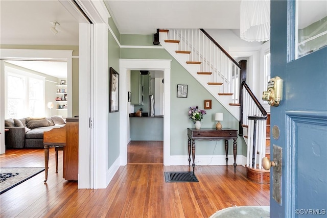 entrance foyer with hardwood / wood-style floors, stairs, and baseboards