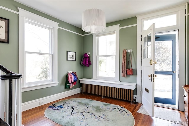 foyer entrance with radiator heating unit, baseboards, and hardwood / wood-style floors