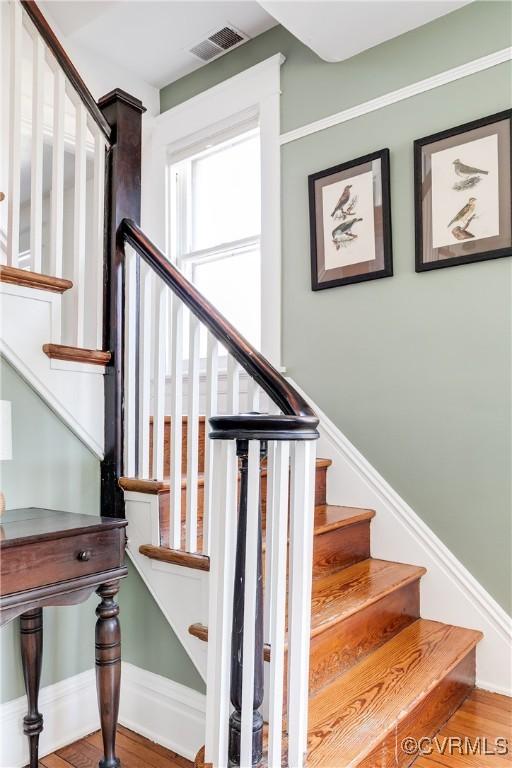 stairs with visible vents, baseboards, and wood finished floors