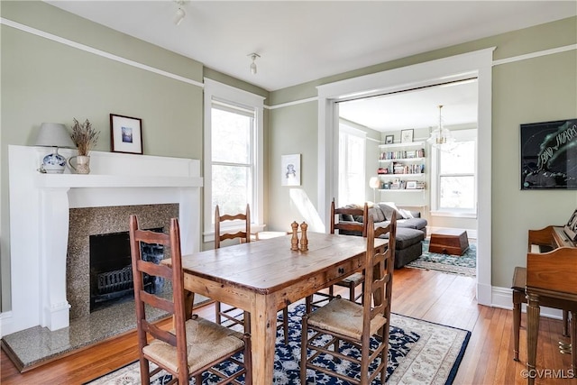 dining area with a wealth of natural light, light wood-style flooring, a fireplace, and baseboards