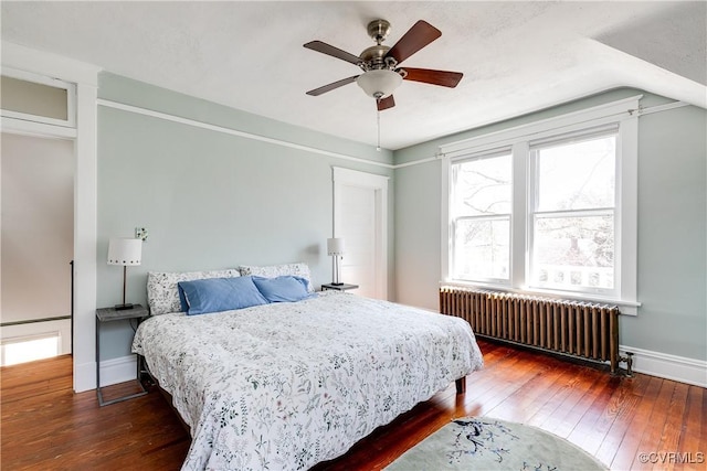 bedroom with hardwood / wood-style floors, radiator, a ceiling fan, baseboards, and lofted ceiling