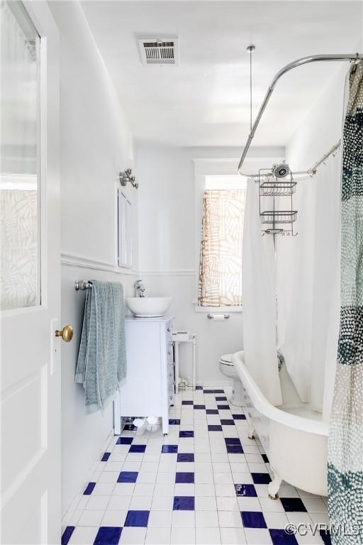 bathroom featuring tile patterned floors, visible vents, toilet, shower / bath combination with curtain, and vanity