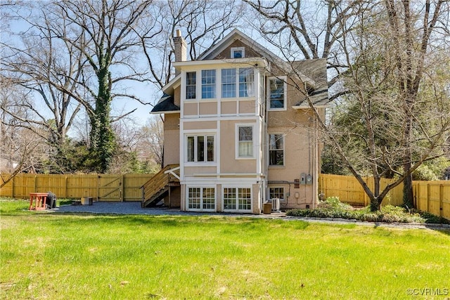 back of property featuring stairs, a lawn, a fenced backyard, and a chimney