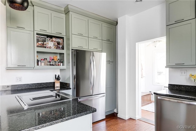 kitchen with open shelves, dark stone counters, appliances with stainless steel finishes, and wood finished floors