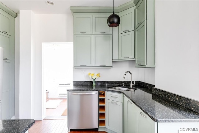 kitchen featuring dark stone counters, green cabinets, a sink, stainless steel dishwasher, and decorative light fixtures