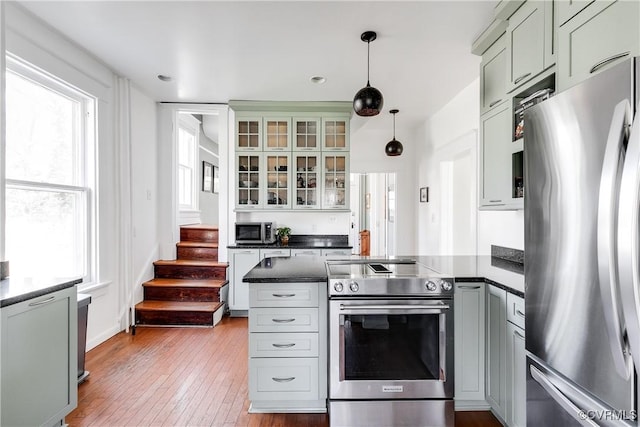 kitchen featuring a wealth of natural light, dark countertops, appliances with stainless steel finishes, and a peninsula