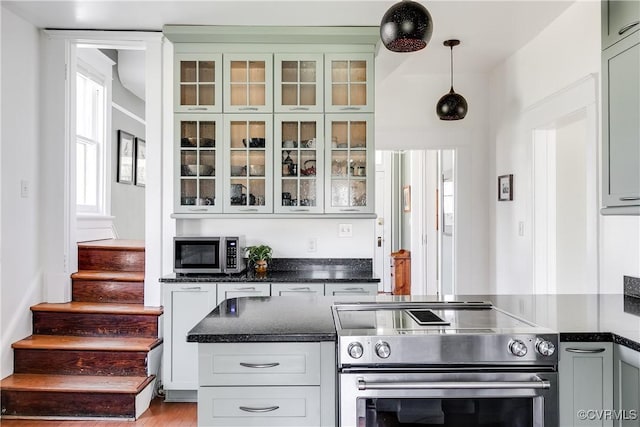 kitchen with pendant lighting, glass insert cabinets, and appliances with stainless steel finishes