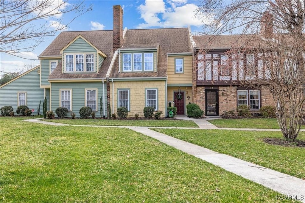 multi unit property with a chimney, a front lawn, and roof with shingles