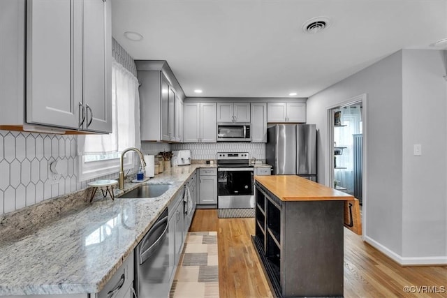 kitchen with light wood-style flooring, gray cabinetry, stainless steel appliances, wood counters, and visible vents