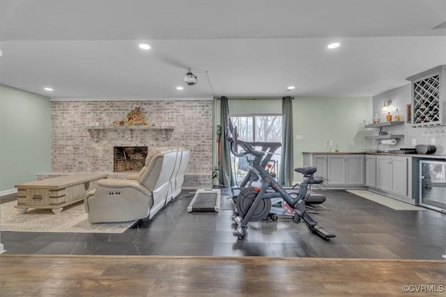 exercise area featuring beverage cooler, brick wall, indoor wet bar, and a fireplace