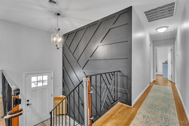 entrance foyer with visible vents, a notable chandelier, baseboards, and wood finished floors