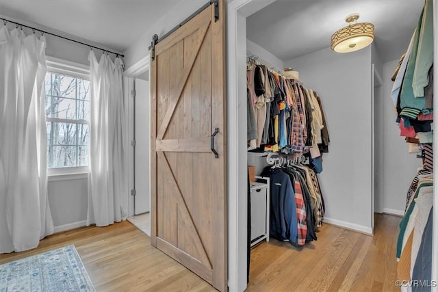 walk in closet with light wood-style floors and a barn door