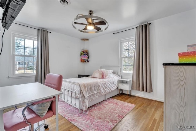 bedroom with ceiling fan, wood finished floors, and visible vents