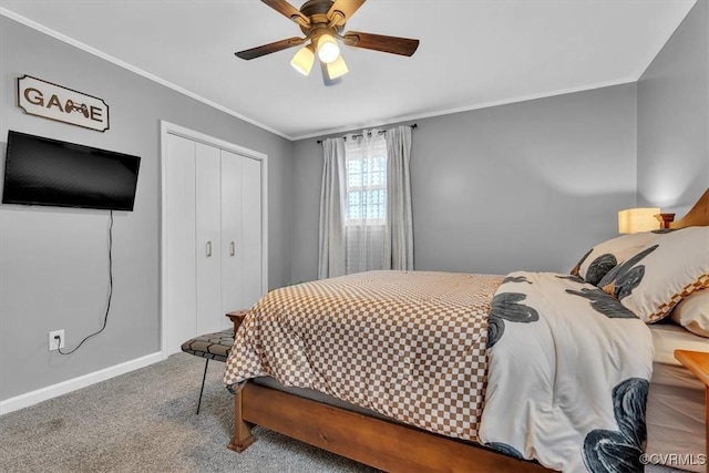 carpeted bedroom featuring a ceiling fan, baseboards, ornamental molding, and a closet