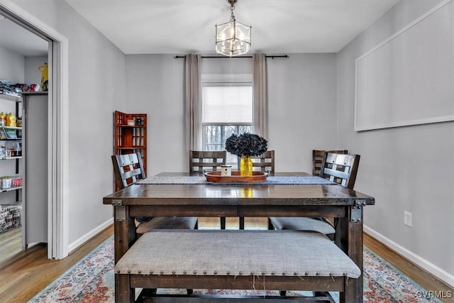 dining room featuring a notable chandelier, baseboards, and wood finished floors