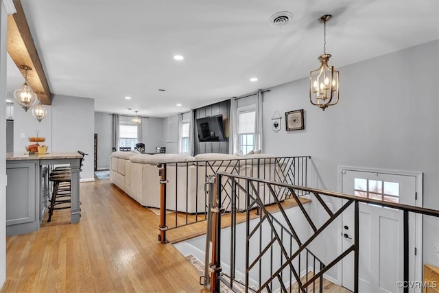 kitchen featuring a breakfast bar area, a notable chandelier, visible vents, light wood-style floors, and gray cabinets