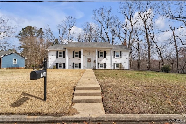 neoclassical / greek revival house featuring a front yard, covered porch, and a chimney