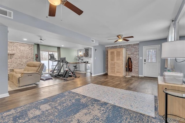 interior space with brick wall, wood finished floors, visible vents, and baseboards