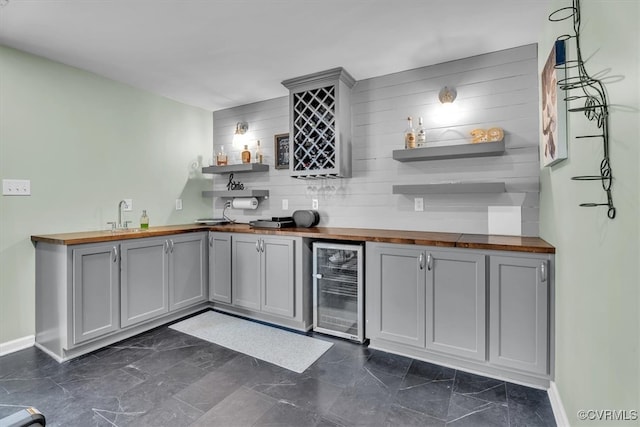 bar featuring beverage cooler, indoor wet bar, baseboards, and decorative backsplash