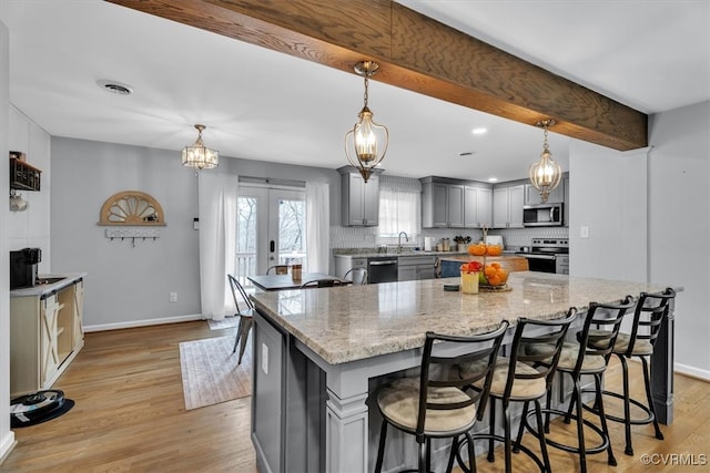 kitchen featuring tasteful backsplash, gray cabinetry, appliances with stainless steel finishes, beamed ceiling, and french doors