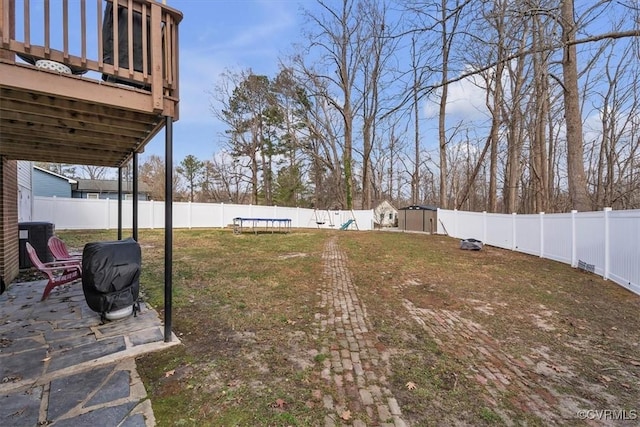 view of yard with a fenced backyard, a trampoline, an outbuilding, and a patio