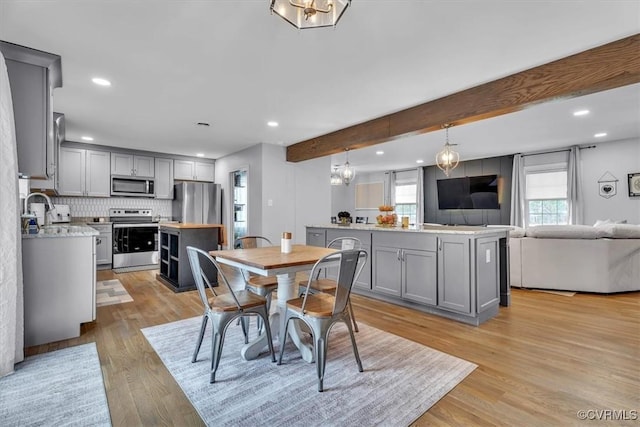 dining space featuring light wood finished floors, beamed ceiling, and recessed lighting