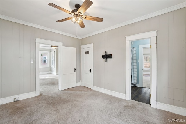 empty room with a ceiling fan, crown molding, and carpet flooring