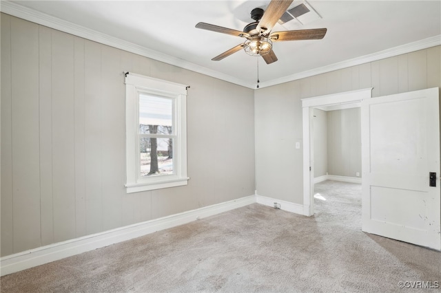 carpeted spare room with ceiling fan, ornamental molding, and baseboards