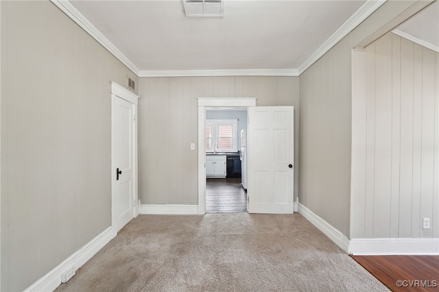 carpeted empty room featuring a sink, visible vents, and crown molding