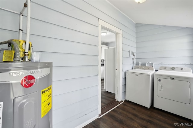 washroom with dark wood-type flooring, washing machine and dryer, electric water heater, and wood walls