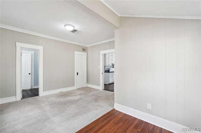 unfurnished room with baseboards, visible vents, dark colored carpet, and crown molding