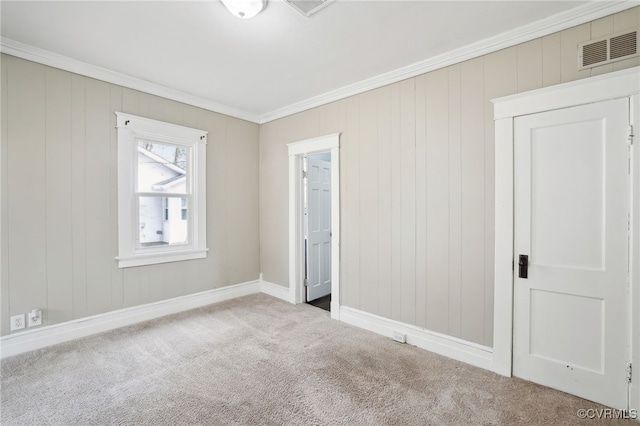 carpeted empty room featuring baseboards, visible vents, and crown molding