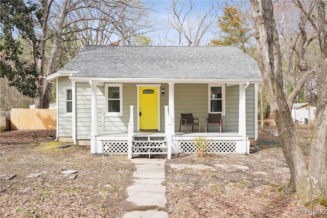 bungalow-style house with a shingled roof, fence, and a porch