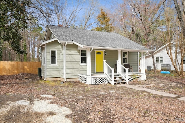 bungalow-style house featuring a shingled roof, covered porch, and fence