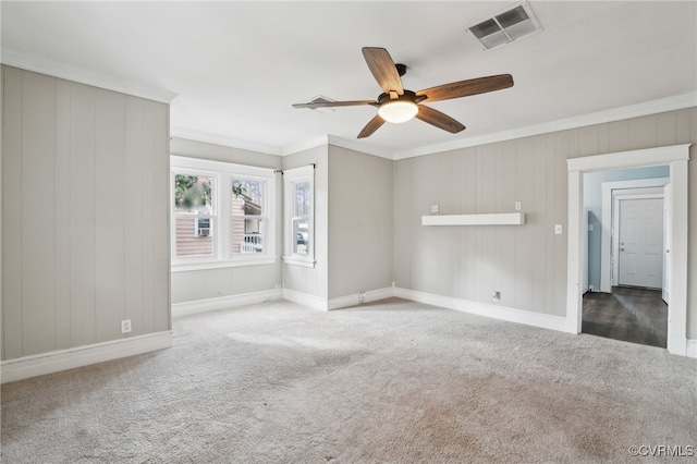 carpeted spare room featuring a ceiling fan, baseboards, visible vents, and crown molding