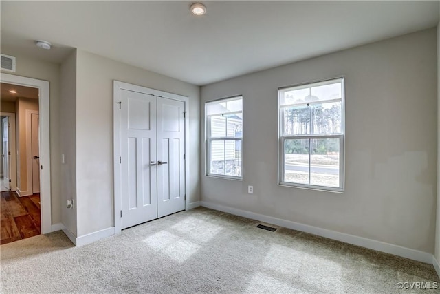 unfurnished bedroom with visible vents, a closet, baseboards, and carpet flooring